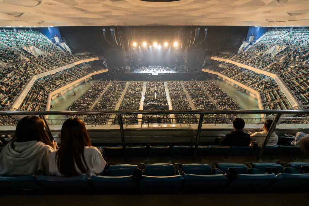 日本武道館の2階スタンド席からステージとアリーナ全体を見下ろすコンサート会場の様子
